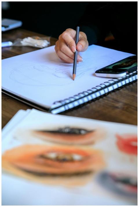 Close-up of an artist's hand drawing a portrait wi