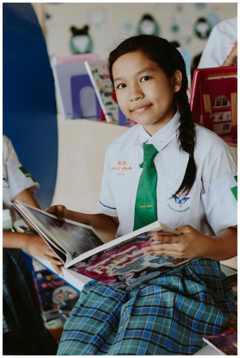 Young Asian girl reading a book in a school librar