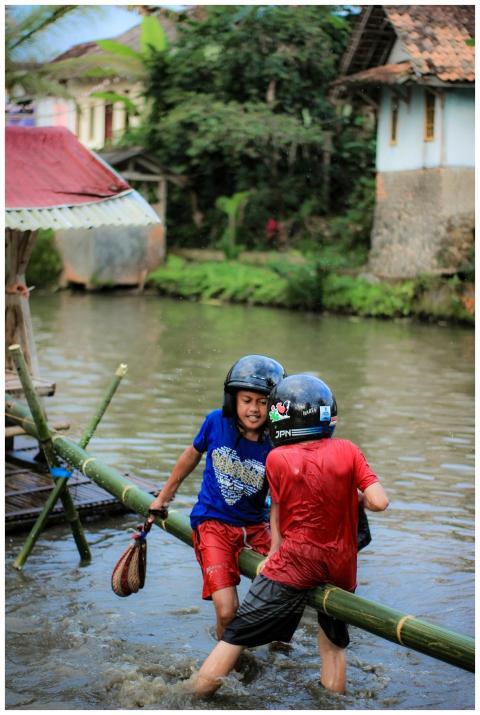 Children playing on a bamboo raft in a river in Ta