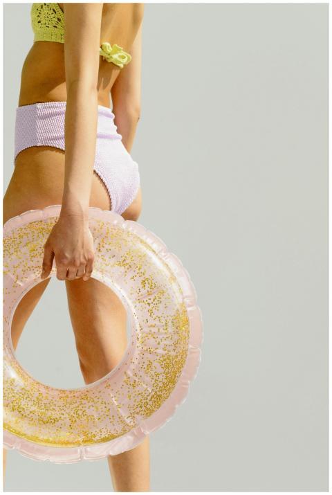 A woman in swimwear with a glittery swim tube, rea