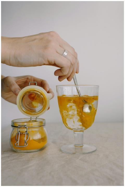 A close-up of a person stirring turmeric in a glas
