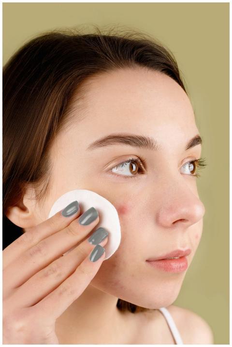 Young woman using a cotton pad on her face for ski