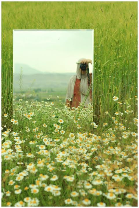 A woman in nature using a mirror for creative phot