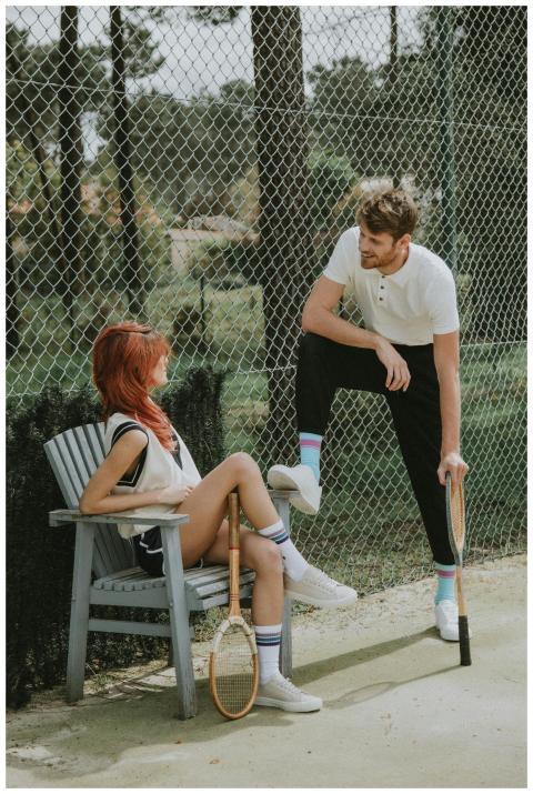 Two young adults share a friendly chat on a tennis