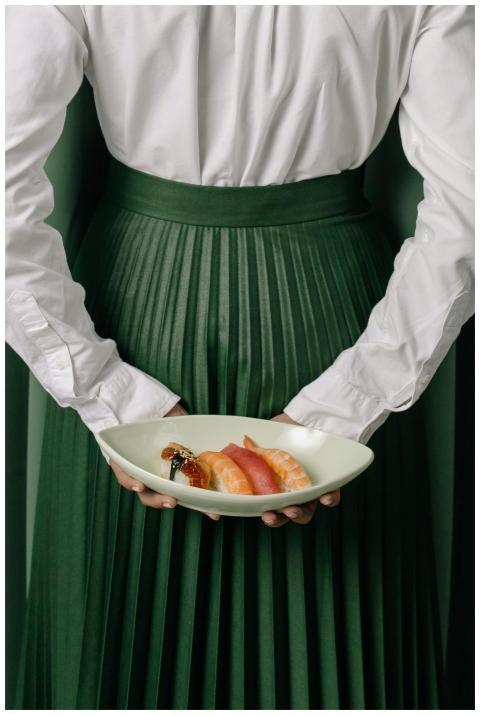 A person elegantly presents a plate of sushi, show