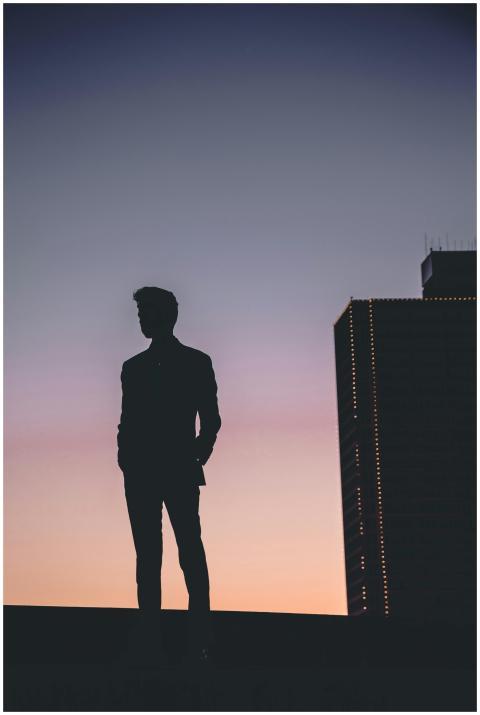 Silhouette of a man standing against a colorful Fo