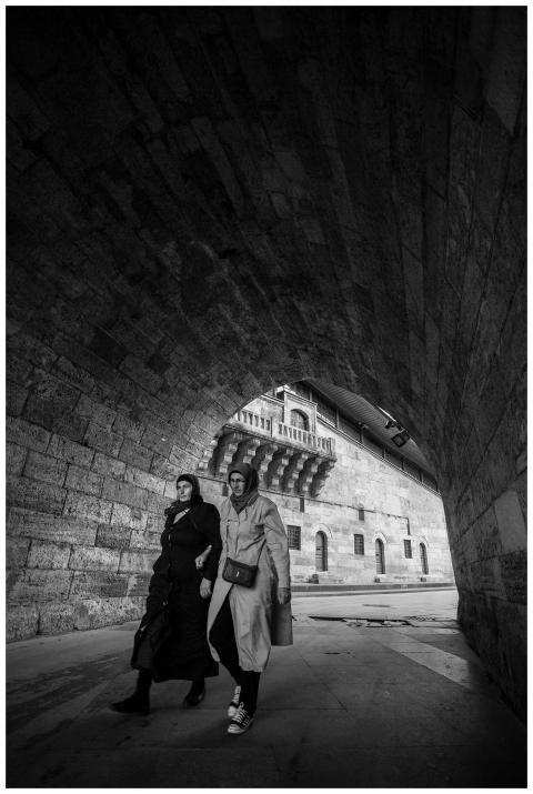 Two women walking under a stone archway in İstanbu