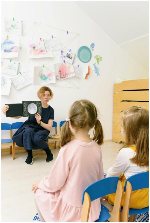 A teacher shows a book to children in a creative k