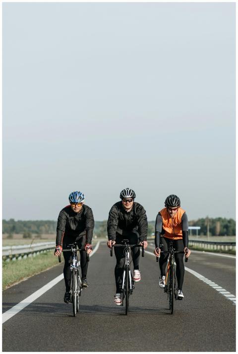 Three cyclists riding together on an open road, en