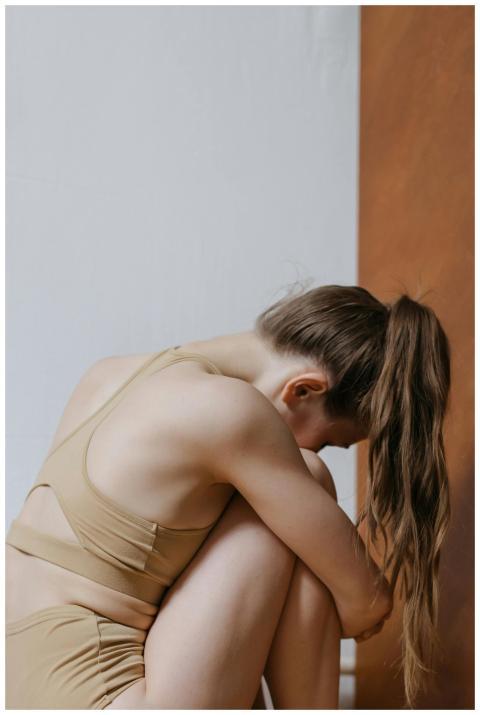 A woman sitting with her knees drawn up, conveying