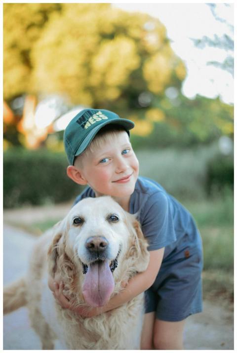 A joyful child in a blue outfit hugs a happy golde
