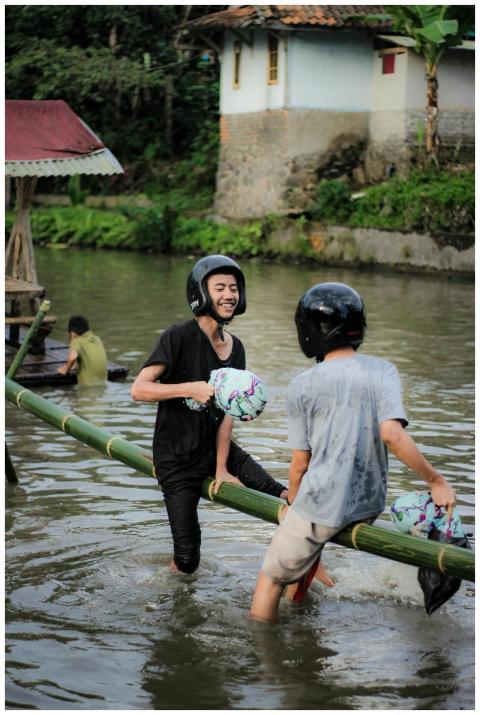 Two young men in helmets enjoy balancing on a bamb
