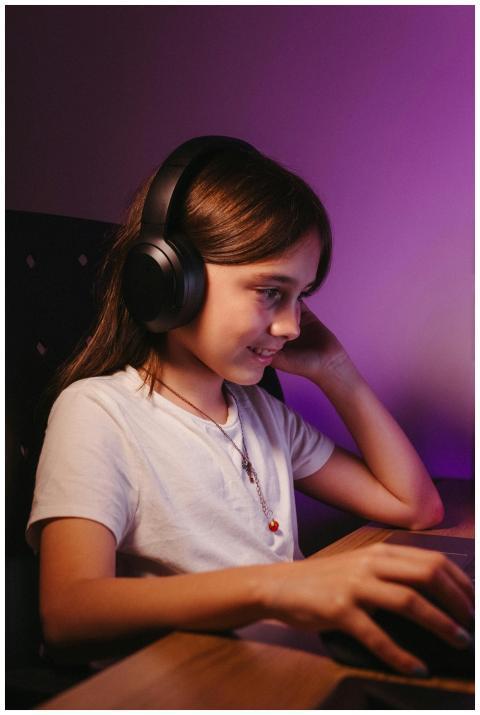 A young girl wearing headphones smiling as she use