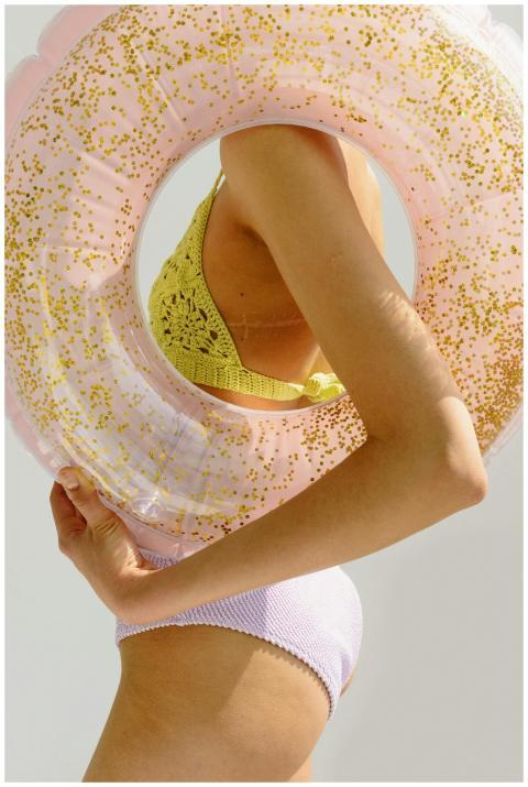 Stylish swimwear model holding a pink glittery swi