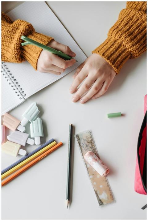 Hands writing in open notebook surrounded by color