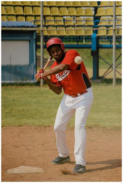 An athlete in a red uniform swinging a baseball ba