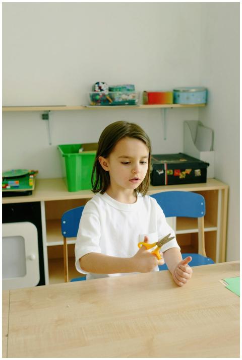 Young child in a classroom setting using scissors