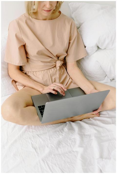 A woman in casual attire using her laptop while si
