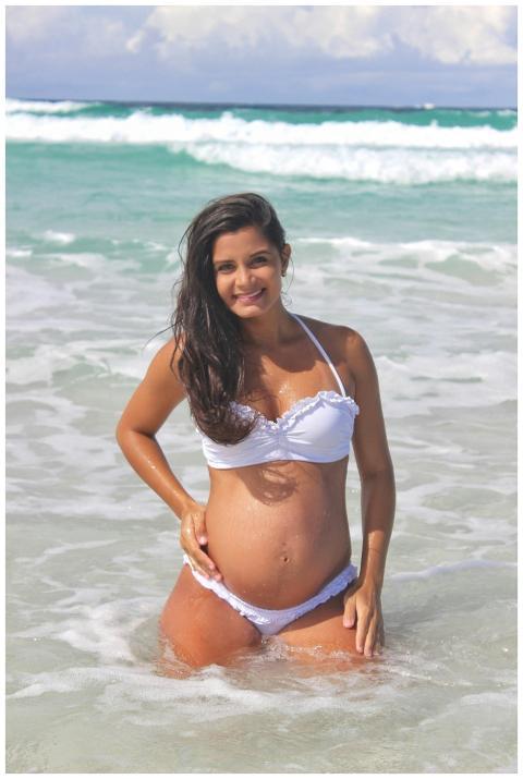 Pregnant woman in a white bikini enjoys sunny beac