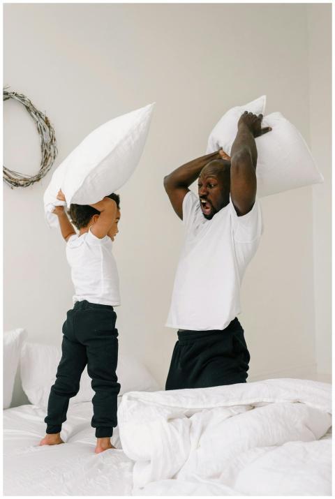 Father and son having a playful pillow fight on a