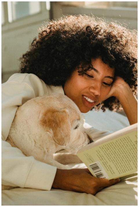 A joyful woman reads a book while relaxing indoors