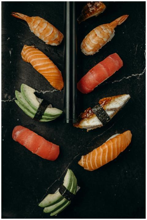 Elegant flat lay of assorted sushi pieces on a dar