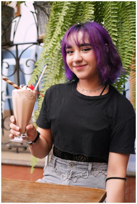 Smiling young woman with purple hair holding a cho