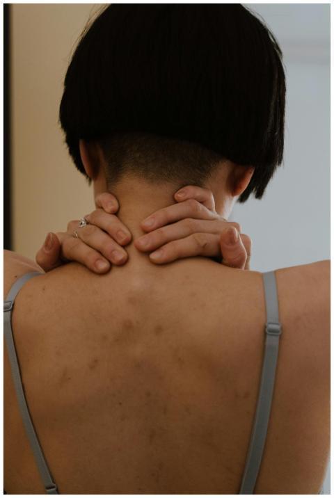 Close-up of a person with short hair, hands on nec