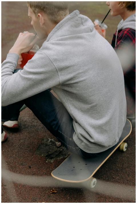 Teens sitting with skateboards, drinking cold beve