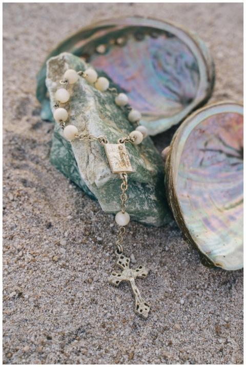 A detailed shot of a rosary placed on sand with se