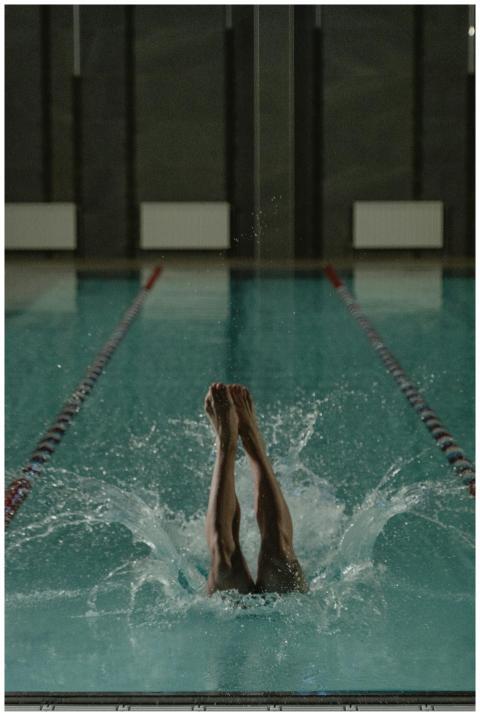 A person diving into an indoor swimming pool creat