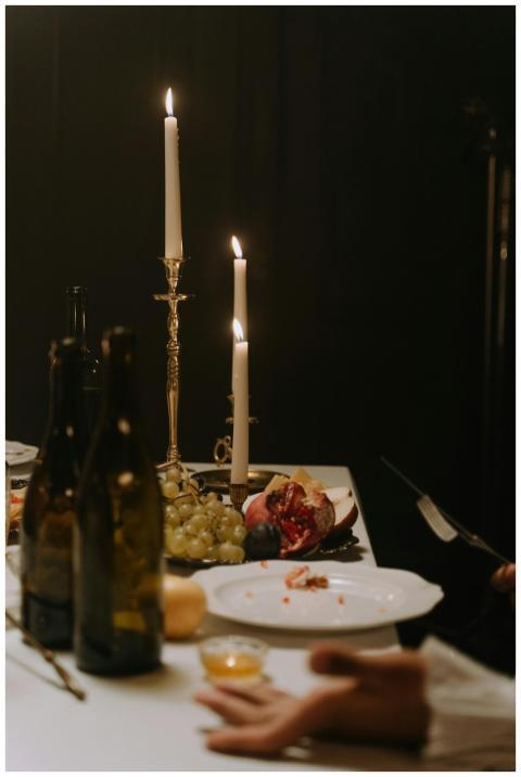A moody candlelit dinner scene featuring wine bott