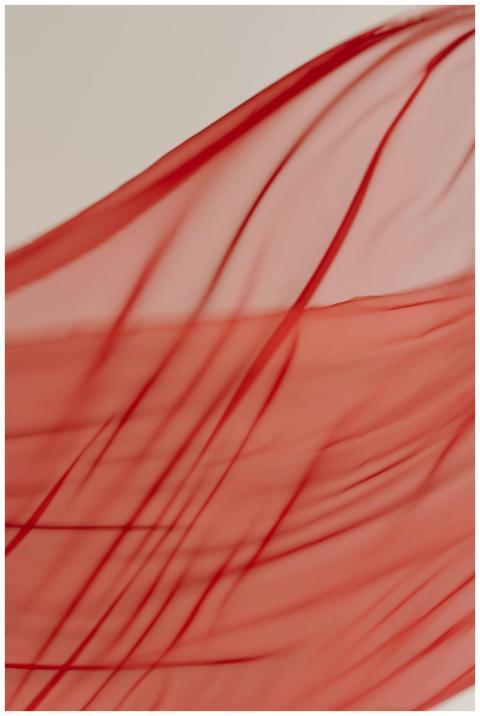 Close-up of red sheer fabric flowing, capturing te