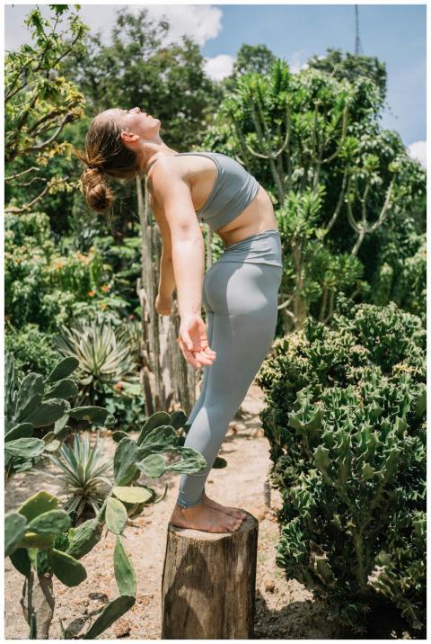 A woman practicing yoga on a tree stump surrounded