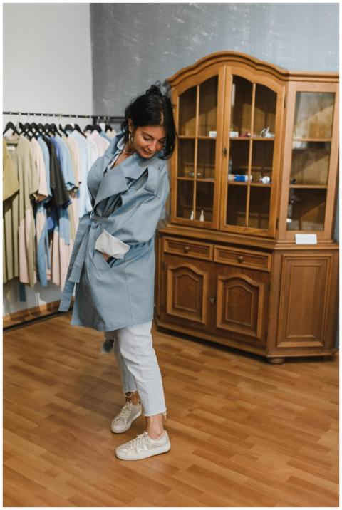 A woman tries on a blue trench coat in a stylish c