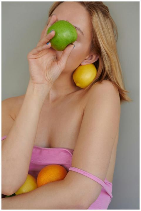 Woman in pink holding citrus fruits promoting vita