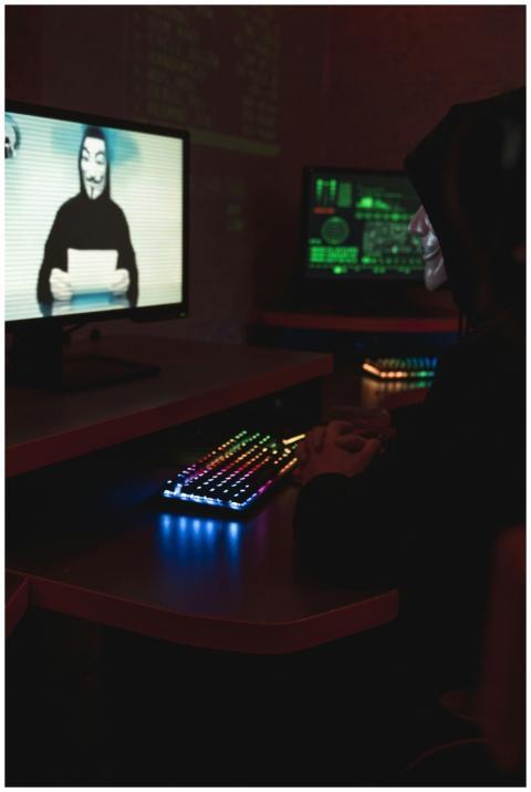 A hacker wearing a Guy Fawkes mask sitting in a di