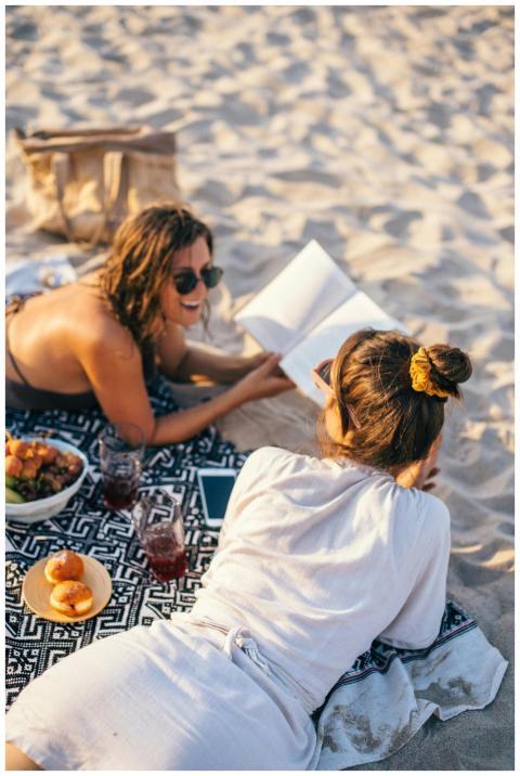 Two women relaxing with a picnic on a sunny beach