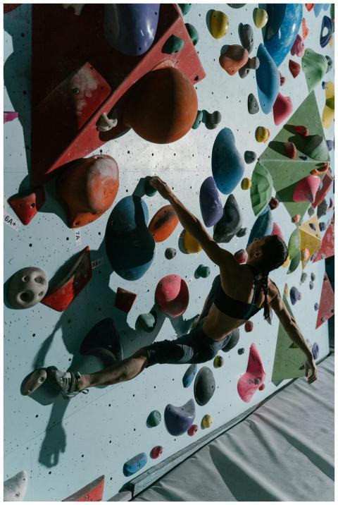Woman scaling colorful indoor climbing wall showca