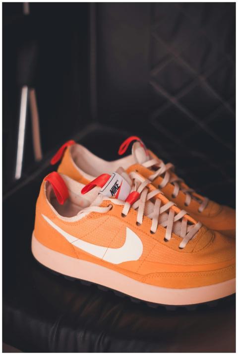 Stylish orange sneakers with white swoosh against