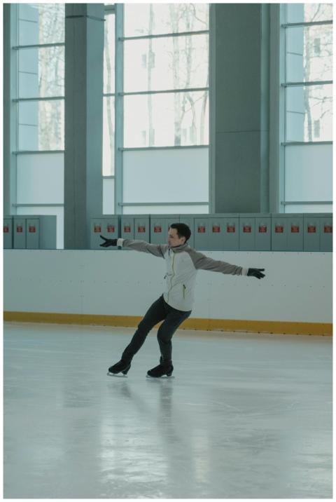 Figure skater in a gray jacket gracefully gliding