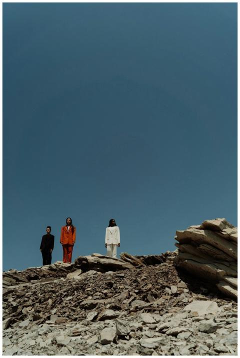 Three businesswomen in attire pose on rocky terrai