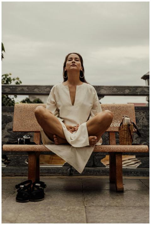 Woman in lotus pose meditating on a bench outdoors