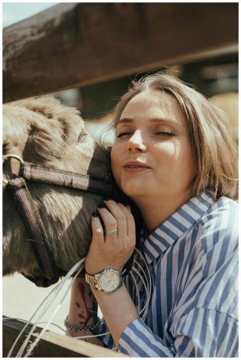 A young woman interacts joyfully with a donkey in