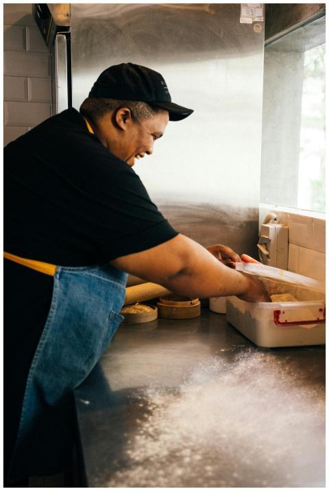 Smiling chef kneading dough in an industrial kitch
