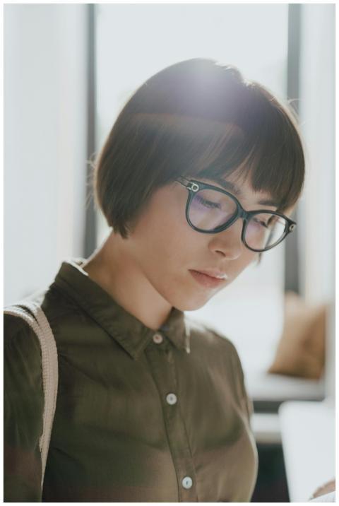 A thoughtful young woman reading in a sunlit books