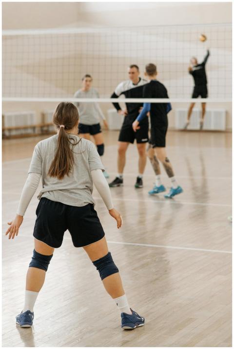 Group of athletes playing volleyball indoors, show