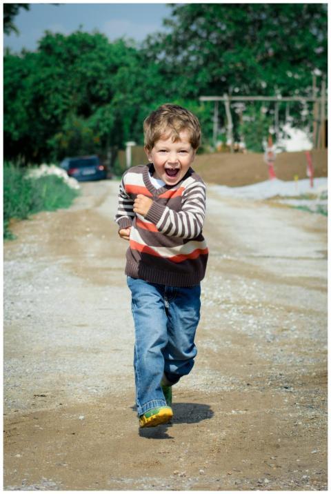 A young boy joyfully runs down a path, showcasing
