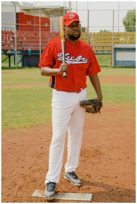 A male baseball player in red uniform with bat at