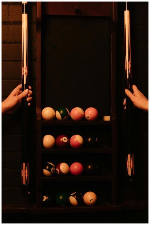 A warm-toned image of a billiard setup with cue st